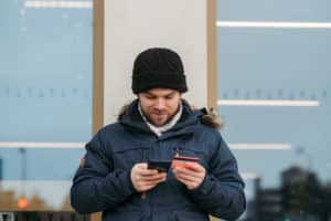 Cheerful man entering details of credit card on smartphone on street
